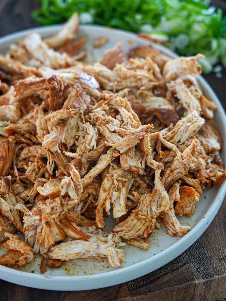 Shredded chicken neatly arranged on a plate, ready for use.