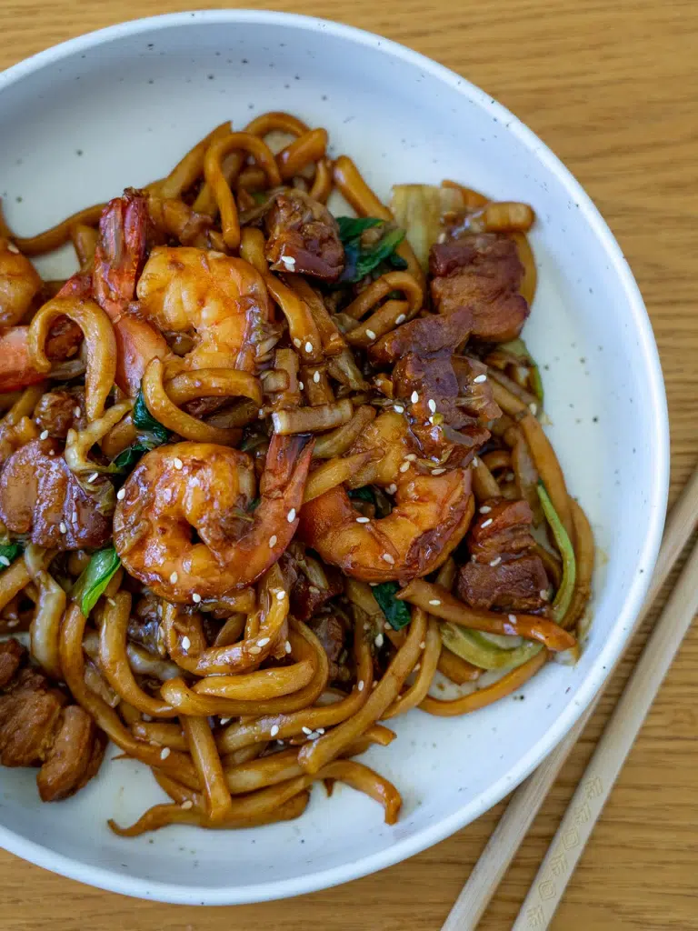Malaysian-inspired Hokkien Mee served on a plate with chopsticks beside it.