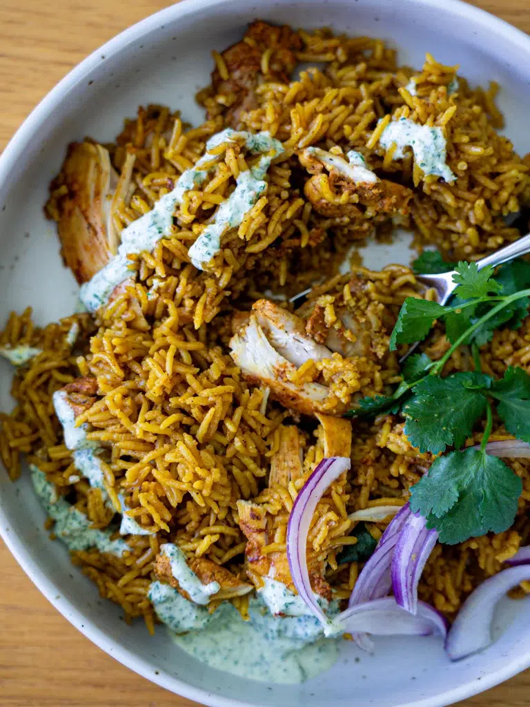 Overhead plated, spoon scooping cut chicken and rice