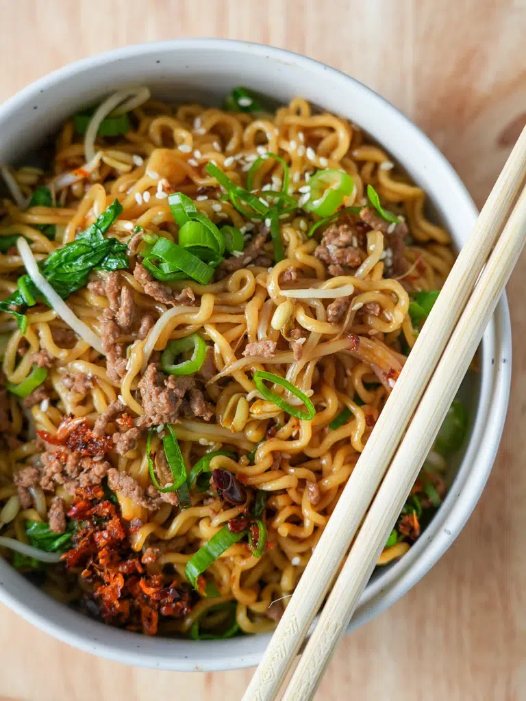 Close-up shot of beef ramen noodles and a pair of chopsticks on top.