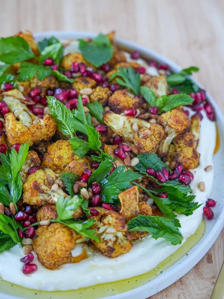 Close-up of roasted cauliflower salad on a white plate, highlighting the vibrant ingredients